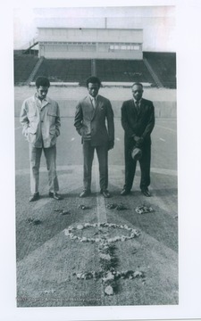 Two Marshall football players, who were injured and didn't fly with the team on a plane which crashed and killed all 75 aboard, visit a symbolic wreath of flowers on Marshall's football field with the father of one of the victims. From left: Felix Jordan, Cincinnati, OH.; Nat Ruffin, Quincy, Fla.; and Lucian Sanders, Tuscaloosa, Ala., father of football player Larry Sanders.