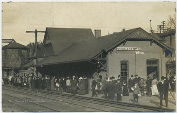 A crowd fills the station center as they wait for the train. 