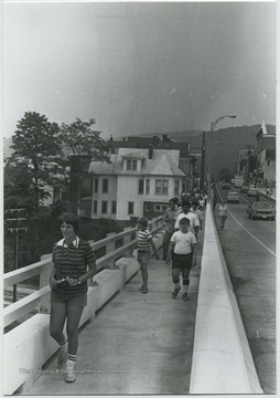 Unidentified people walk along the pedestrian path on the bridge. Old Toll House is pictured in the background on the left. 