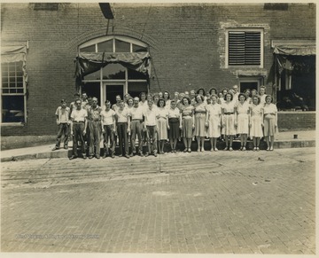 Employees pose for a group picture beside the building located on 2nd Avenue. Subjects unidentified. 
