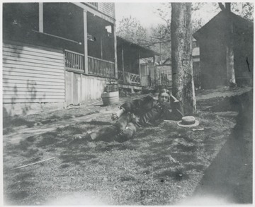 Murrell is pictured in his yard under a tree. Original photo is captioned  'Sleeping Beauty'. The house is located at the corner of 5th Avenue and Summers Street. Note the side porches. 