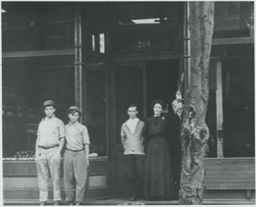 The building is located in what is today the Alderson Shumate Building. Woman is Elizabeth Heatwell, who worked in this bakery. Subjects unidentified. 