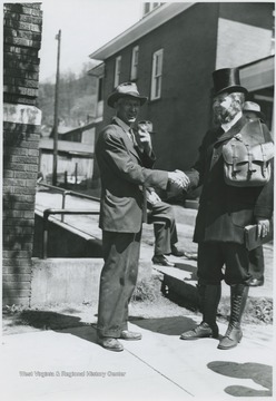Moorman Parker, right, dressed as the rider for the re-enactment shakes hands with an unidentified man in front of the church located on 3rd Avenue.