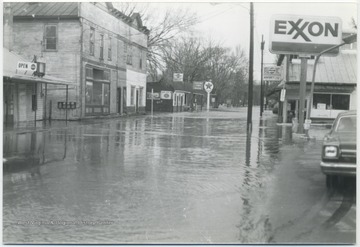 View of a submerged street with buildings on either side. Waters reached anExxon station to the right. 
