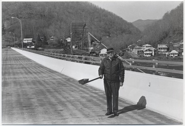 Kirk holds an old toll bridge pan on the new New River bridge. The old New River bridge is pictured in the background. 