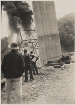 Three men observe the damage after the span of the bridge collapsed into the mouth of the Bluestone River.Five workmen killed and four injured when the 300-ton span buckled and folded downward into the mouth of Bluestone River.A week after the collapse the men began dismantling the twisted span, using a never before used technique by burning the steel beams with chemicals.