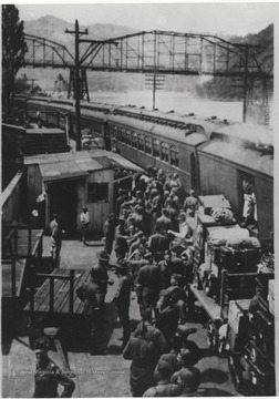 A group of men crowd the passenger train at Hinton Station while loading their luggage. 