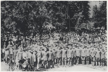 A large crowd of men in their uniforms are pictured beside the park among their peers. Subjects unidentified.