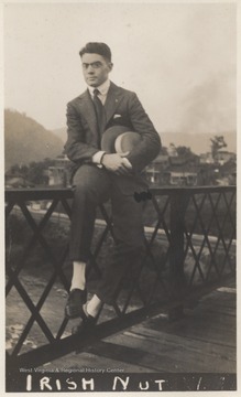 The photograph is titled, "Irish Nut." An unidentified man sits on the railing while holding his hat. 