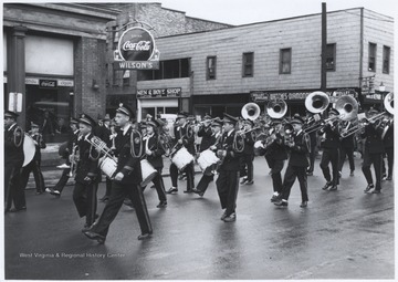 Young boys in their band uniforms march down the street with their instruments in hand. Subjects unidentified. 