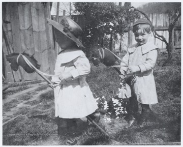 The two children play outside with stick horses. The yard is attached to the John Flanagan and R.O. Murrell home located on the corner of 5th Avenue and Summers Street. 