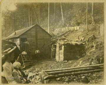 This image is part of the Thompson Family of Canaan Valley Collection. The Thompson family played a large role in the timber industry of Tucker County during the 1800s, and later prospered in the region as farmers, business owners, and prominent members of the Canaan Valley community.Men and women are seen throughout the camp.Caption on back of photo reads: "Possibly Bob Eastman?"