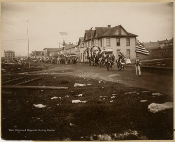A group of parade participants in patriotic garb make their way down the street.This image is part of the Thompson Family of Canaan Valley Collection. The Thompson family played a large role in the timber industry of Tucker County during the 1800s, and later prospered in the region as farmers, business owners, and prominent members of the Canaan Valley community.