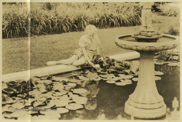 The girl, who is unidentified, smiles as she pulls a flower from the water. 
