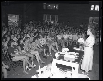 A group of young, female campers listen as an instructor speaks about frozen food. Subjects unidentified. 