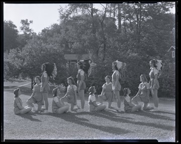 The girls pose on the lawn wearing Native American headdresses. Subjects unidentified. 