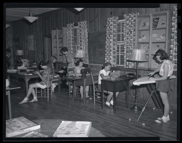 A group of unidentified girls sit behind sewing machines as they work through their class activity. 