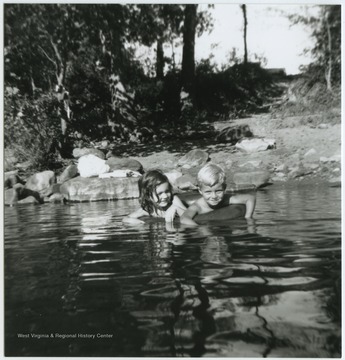 A boy and girl share an inner tube while floating in the waters, also known as Greenbrier Springs, which is located off of the Greenbrier River. Subjects unidentified. 