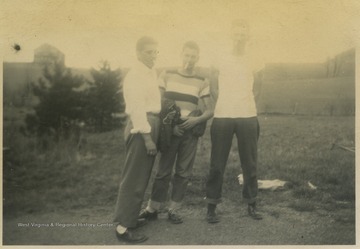 Three boys on the baseball team pose together for a group photo. Subjects unidentified. 