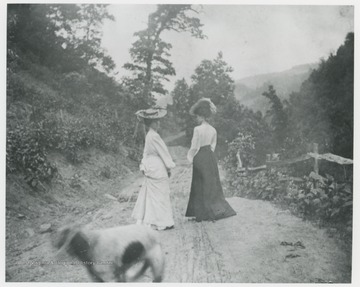 Mrs. Ro. Murrell and another woman walk down a dirt road.