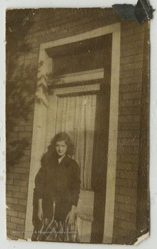An unidentified female student stands outside of a building. 