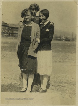 Three unidentified students pose on the lawn with the high school building in the background. 