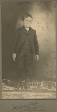 A young boy stands stiffly while looking into the camera.