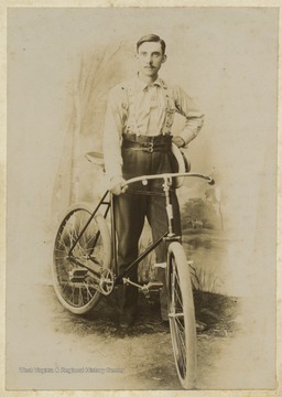 An unidentified male Jollife family member poses with a bicycle.