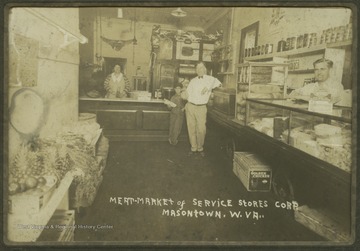 A man and a boy lean against the counter while two employees stand behind separate counters. 