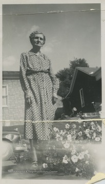 Photo of Ralph McMillan's mother beside a small garden. 