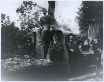 Five unidentified miners pose beside a truck loaded with coal. 
