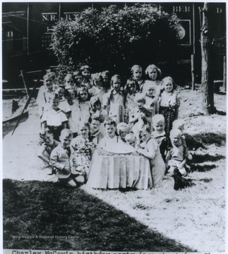 Charley, sitting in the center behind the cake, grew up to be a nationally known person in the entertainment field. This is either his sixth or seventh birthday party. 
