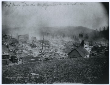 "Mt Hope W. Va. after the conflagration March 24th, 1910"  The majority of the buildings in town have been destroyed.  A number of brick chimneys are left standing after the wooden buildings burned.
