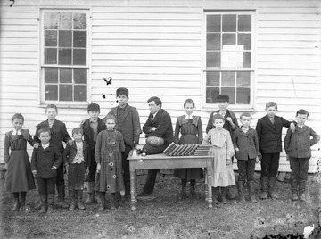 The teacher holding the football in the middle of the photograph is Dock Post. The school was located on the Post family farm. On the right, behind the teacher, is Gay Woodson. 
