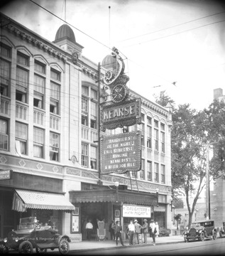 A group of men stand outside of the theater where advertisements of the film, "Daughters of the Night" are displayed. Daughters of the Night came out in 1924.