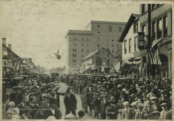 Crowds fill the streets of Morgantown, W. Va. anticipating the parade. In the background is a Union Bank, right, and the building that is now Hotel Morgan, center. 