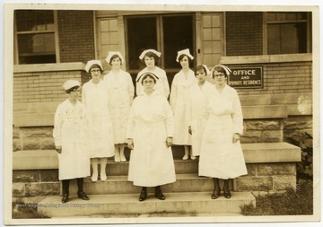 Eight nurses standing outside the Office and Private Residence of the Monongalia County Hospital.