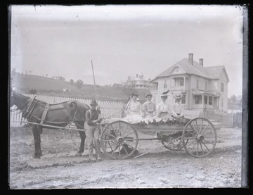 Four girls in a horse-drawn wagon. The house seen in the background on the far right is the Ernest Bowman House, located on what is now the corner of North Main Street and Dogwood Drive.