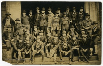 Members of the Mountain Honorary pose in front of a building. Text on the back reads: "Initiates: Glasscock, Brock, Hardy, Winter, Lewis, White, Mullen, Winters, McCoy, Gilmore, Long, Summers."