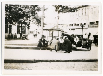 Men sit and talk in front of the courthouse on High Street. J. G. McCrory Co. can be seen in the background, now the site of Reeder and Shuman Attorneys at Law.