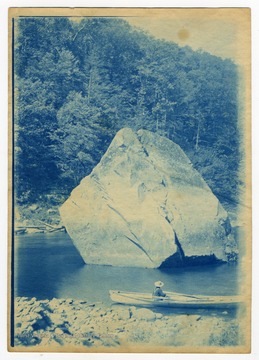 A man in a rowboat pauses by Squirrel Rock, which was submerged with the construction of the Cheat Lake Dam in 1926.