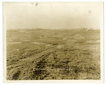 Text on back reads, " 'A' Runway from east side at Station 18 and 60. Rock base at north end being placed. Stock pile of surfacing materials."