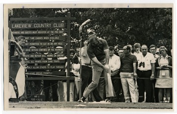 A crowd of spectators watch Arnold Palmer play golf.