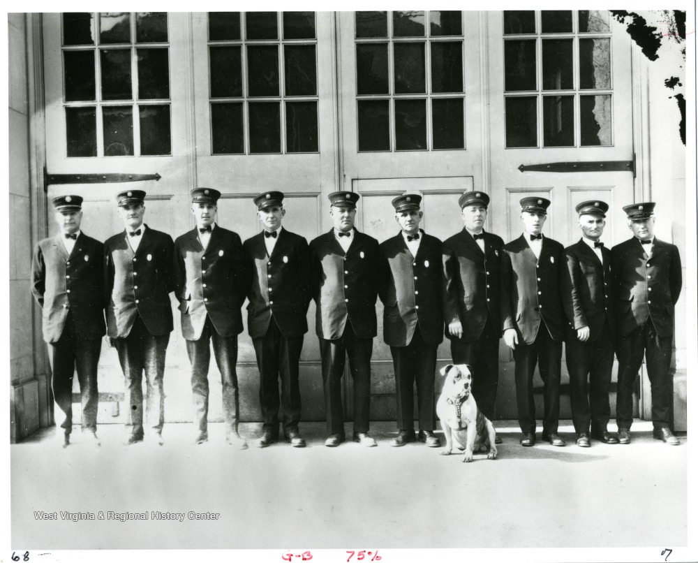 Members of the Morgantown Fire Department, from left to right: "Chief John Hare, John Rich, Mearle Devaughn, Homer Zearley, William Sherman, Rolla Dutton, Plummer Pride, Harry Feck, Dorsey Stalnaker and Friend Barrett. The dog is "Doc," the mascot."Photo appeared in the Morgantown Post on February 23, 1927.