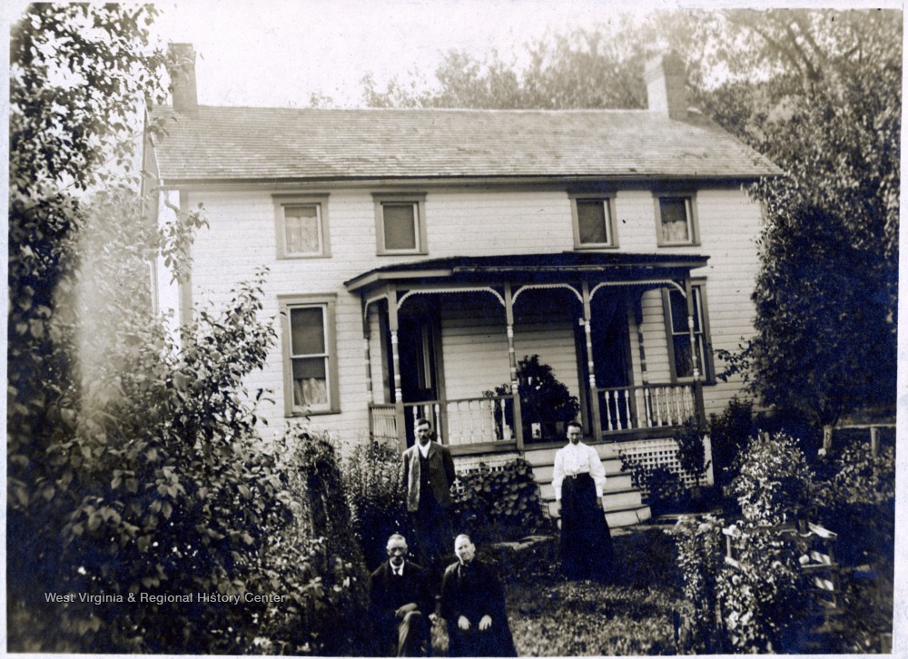 A photograph of two men and two women standing in front of a house.