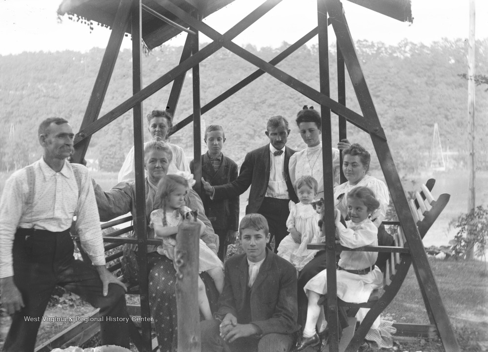 Identified people: Man with mustache on left is Thomas Benton Green, woman on left with child on her lap is Mary Rupert Green, boy in far back is George Green, boy in front is Ray Green, girl holding cat on right side is Virginia Green, and woman next to her is Will Porterfield's wife.