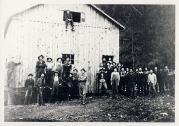Group portrait of lumber workers in front of building.