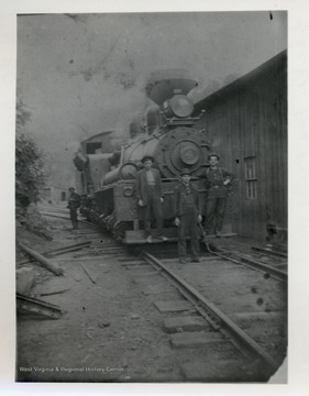 Men standing on and in front of train.  One man off to the side in the back.  Original from C.B. Cromer.
