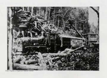 Shay No. 3 engine beside a hill of logs.  