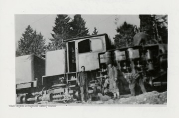 Side view of train engine and three crew members.  